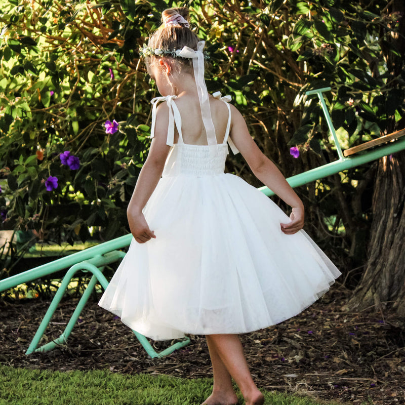Margot ivory tea length tulle dress shown from the back being worn by a young flower girl.