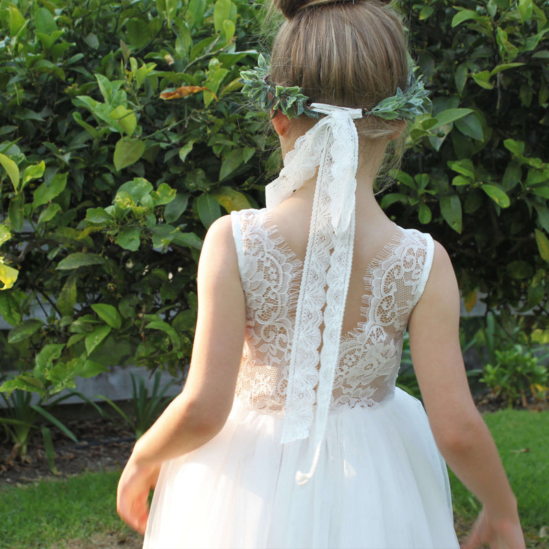 Mia lace and tulle flower girl dress shown from behind on a young girl. Showing the eyelash lace detail of the back. She also wears our Olive flower crown with a lace tie back.