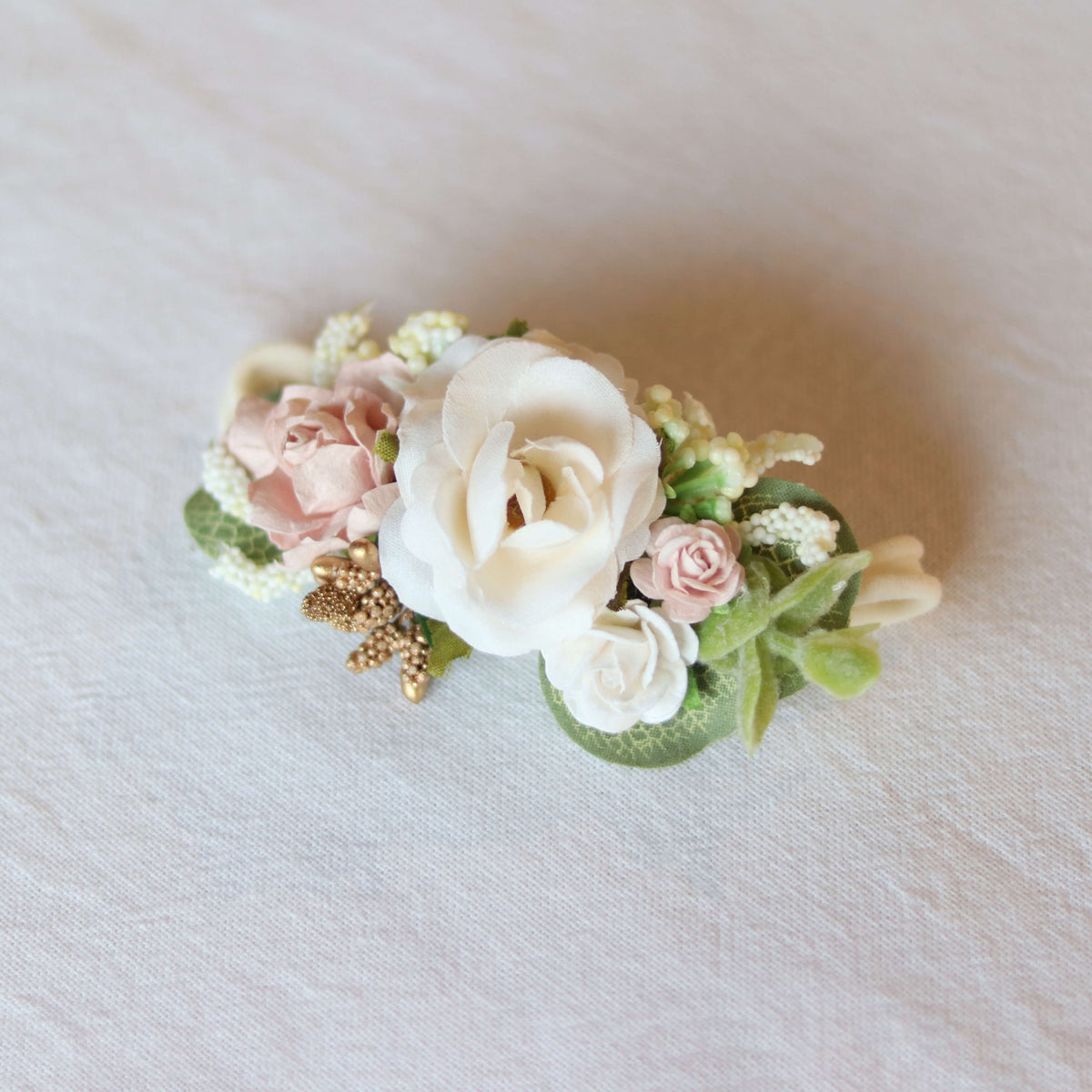 Norah baby girl flower crown on a soft fabric headband, composed of a large ivory flower surrounded by smaller blush and ivory flowers, gold accents and greenery.