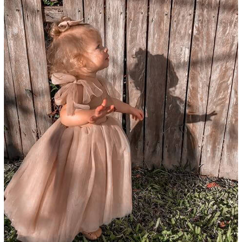 Rosie girls birthday party or flower girl dress shown on a toddler. The dress is champagne colour with tulle bow straps.