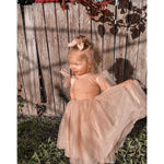 Rosie flower girl dress worn by a toddler. The tulle dress has tulle bow straps and is Champagne in colour.