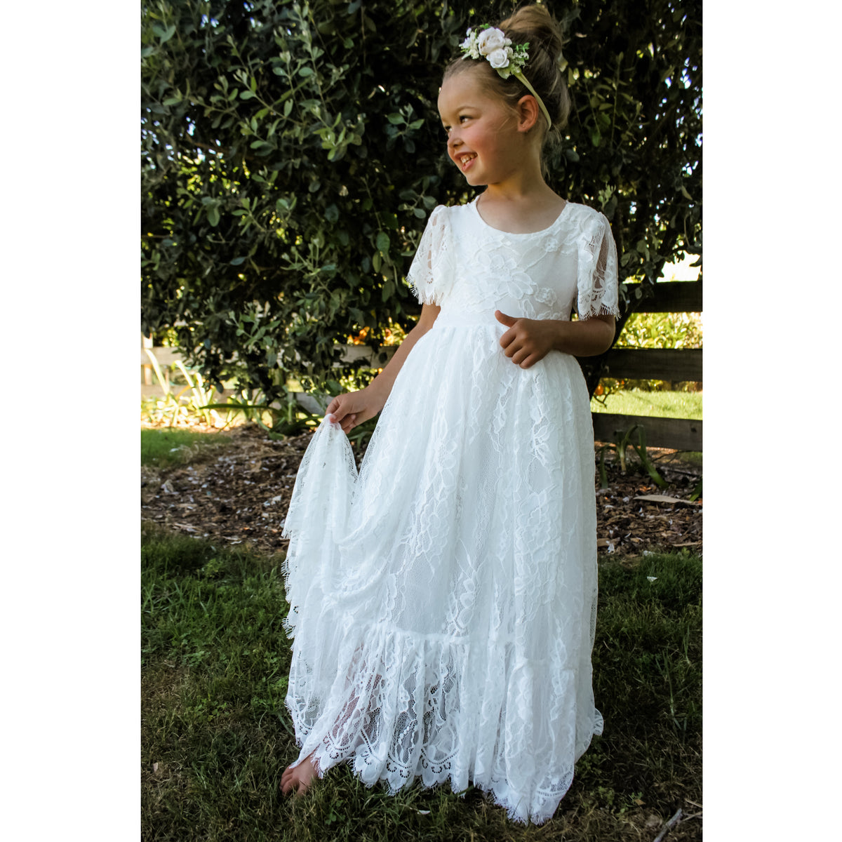 Violette white lace flower girl dress, worn by a flower girl. She also wears our Delilah ivory floral headband.