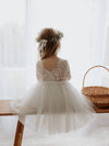 Belle tea length tulle and lace flower girl dress is worn by a young girl.