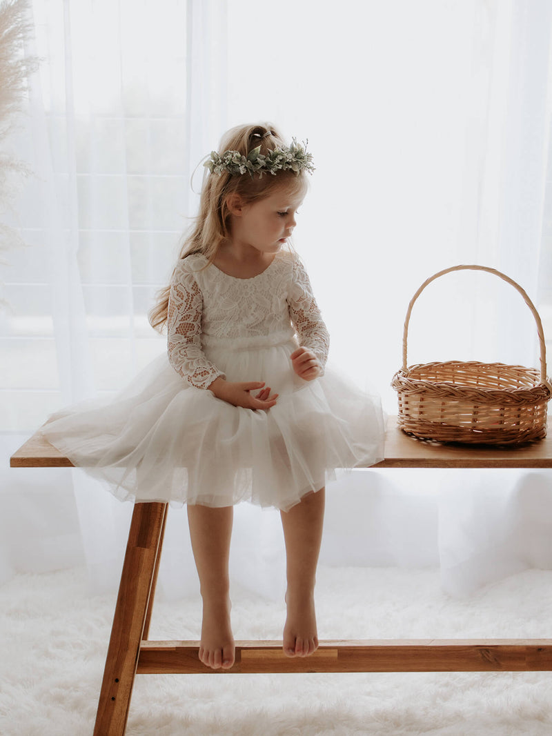 Belle lace and tulle flower girl dress is worn by a young girl, along with a flower crown.