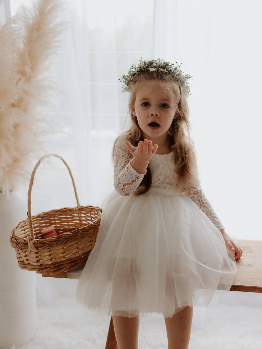 Belle tea length flower girl dress in ivory is worn by a toddler.