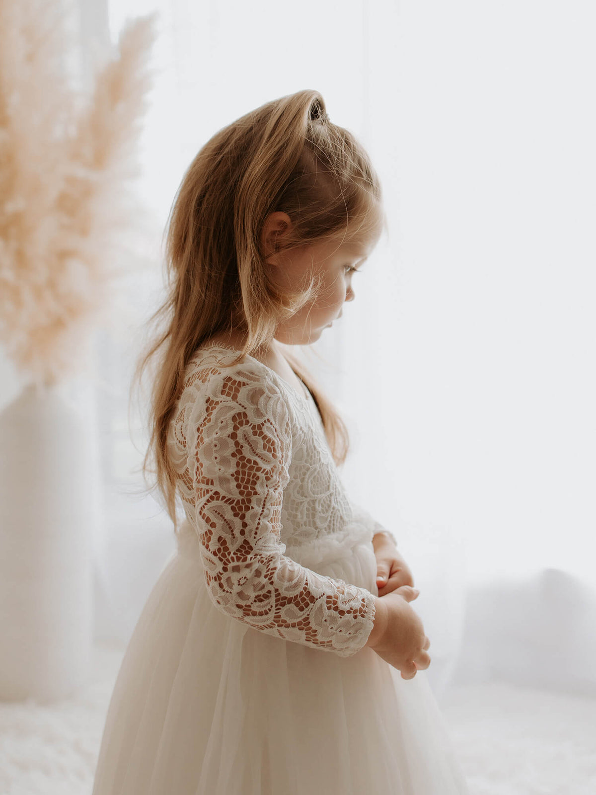 Belle flower girl dress in tea length shown from the side, worn by a young flower girl.