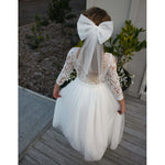 Winter flower girl dress, Belle dress, long sleeve and full length tulle skirt is worn by a young girl. She also wears our large ivory tulle bow.