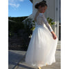 Belle full length lace and tulle flower girl dress in ivory worn by a young girl.