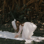 Briar flower girl dress and large tulle hair bow in ivory are worn by a young flower girl.