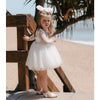 Young girl wears our Briar lace flower girl dress at the beach, she also wears our large tulle hair bow.