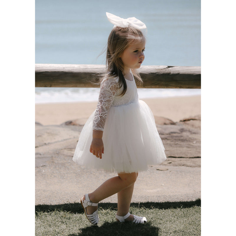 Young flower girl wears our Briar flower girl dress in ivory, along with our large tulle bow hair accessory.