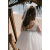 Briar flower girl dress and large tulle bow in ivory are worn by a young girl.