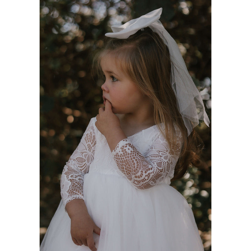 Young flower girl wears our Briar lace flower girl dress and large tulle bow in her hair.