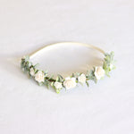 Eden toddler and girls ivory floral headband. Dainty ivory flowers spaced along a base of greenery, a simple neutral flower crown. Set on a soft elastic cream headband.