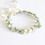 Eden ivory flower crown with small ivory roses on wreath of greenery, with an ivory ribbon.