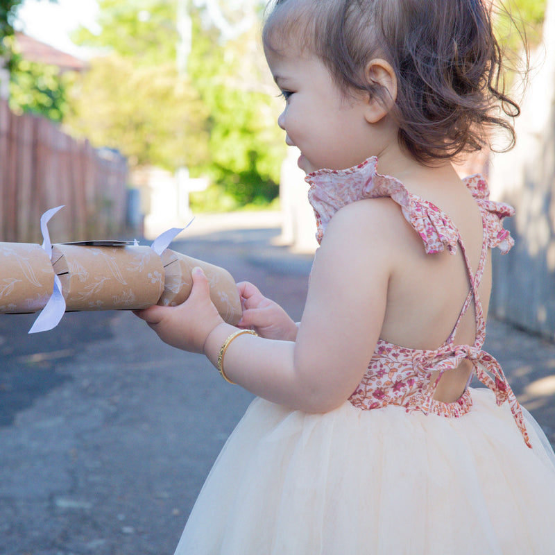 Everly floral tulle romper worn by a toddler. Showing the floral bodice, cream tulle skirt and tie back.