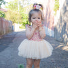 Everly tulle baby romper is worn by a toddler. The romper has a cotton floral bodice and a light cream tulle skirt.