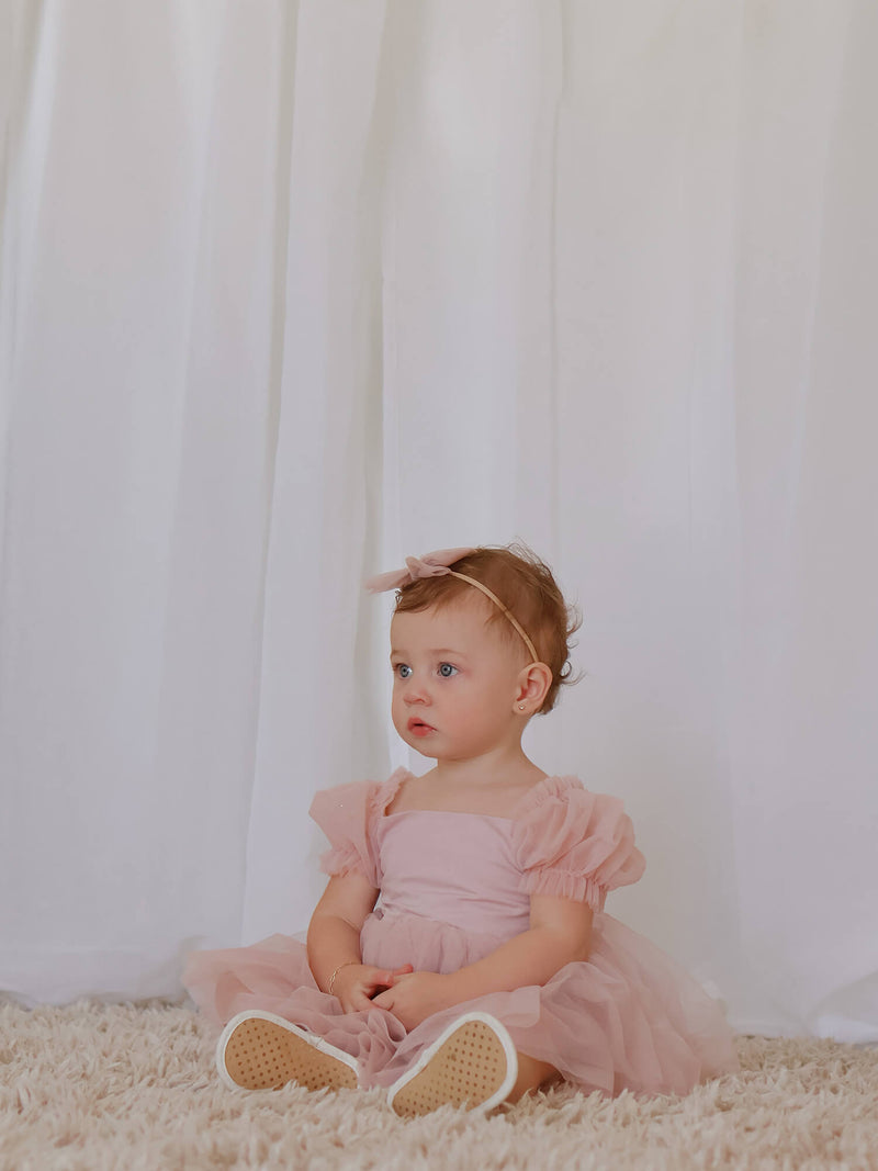 Gabrielle tulle puff sleeve baby flower girl dress in dusty pink, worn by a toddler.