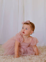 Gabrielle tulle baby flower girl dress along with matching tulle bow headband, worn by a toddler.