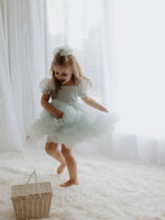Young girl twirls in our Gabrielle tulle flower girl dress in dusty blue.