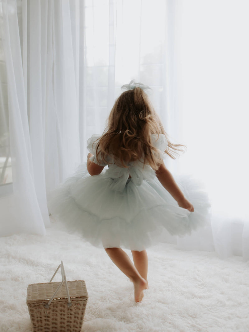 Showing the back of our Gabrielle flower girl dress in dusty blue, showing the tulle bow at the back.