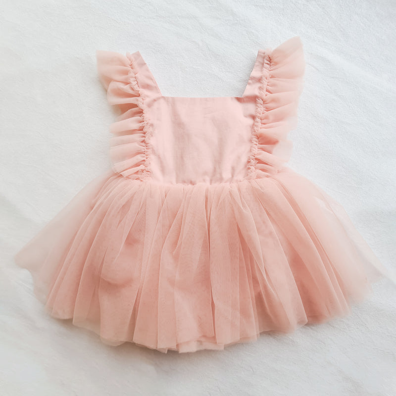 Gigi baby special occasion dress romper shown from the front with tulle details and tulle skirt in a peach blush colour.