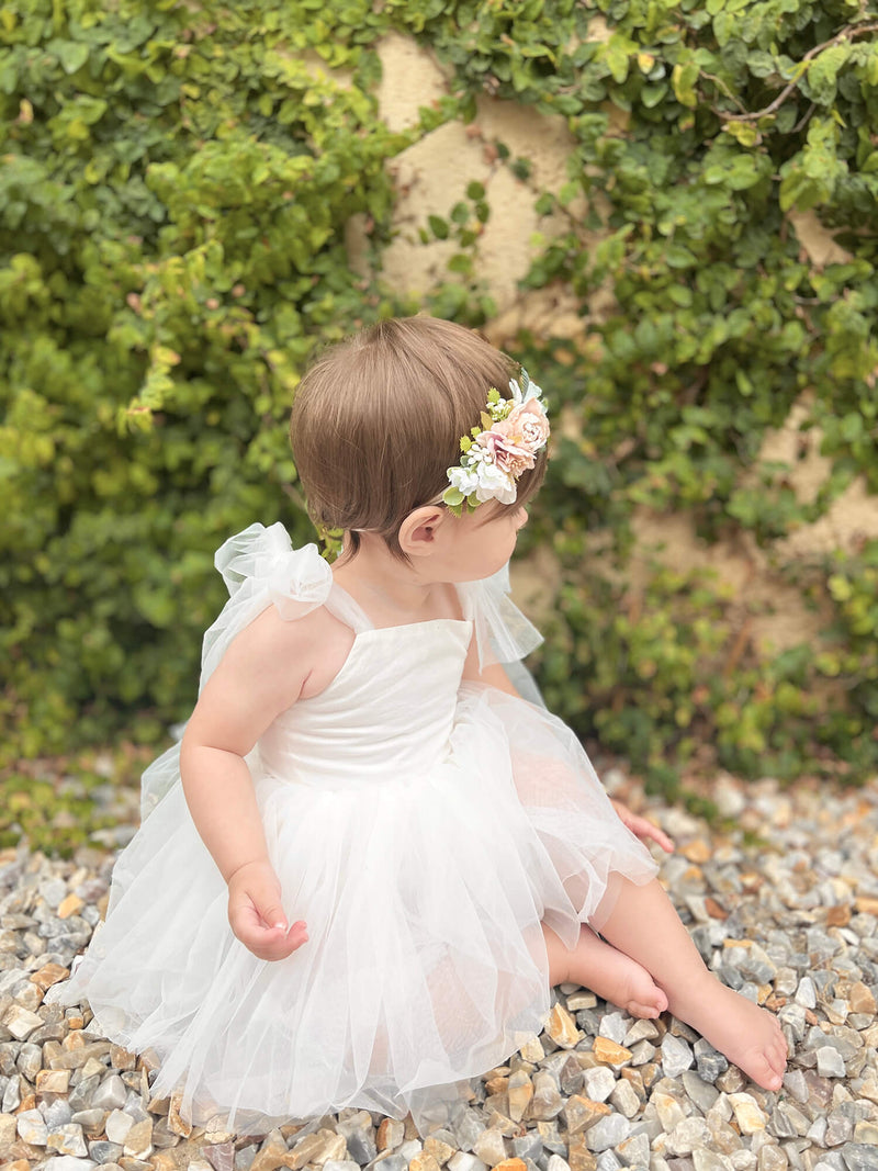 Harper baby flower girl romper with tulle tie sleeves is worn by a baby.