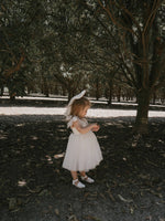 Harper ivory tea length flower girl dress is worn by a toddler. She also wears our large classic tulle bow in her hair.
