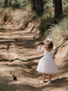Harper white tea length flower girl dress is worn by a young girl, along with our large tulle bow in her hair.