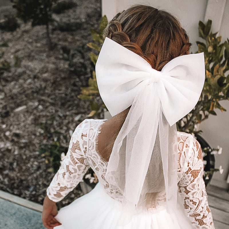 Large tulle bow clip in ivory is worn by a young girl, along with our Belle lace flower girl dress.