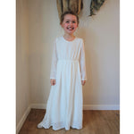 Marlowe full length long sleeve ivory flower girl dress being worn by a young girl..