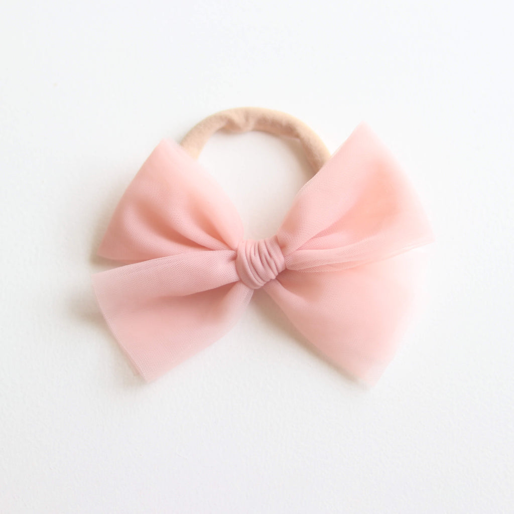 Peachy blush tulle bow on a soft elastic headband, for babies and children.