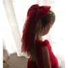 Young girl wears our large Christmas bow in her hair, along with our Rosie Christmas dress in crimson.