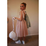 Young girl wears a Rosie tulle dress to a birthday party. She holds a white balloon.