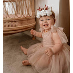 Baby girl wears our Rosie tulle baby romper in dusty pink. With tulle tie sleeves and a soft tulle skirt.