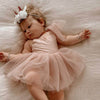 Rosie tulle baby romper with tulle tie sleeves is worn by a baby girl.