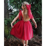 Rosie dress in Christmas crimson is worn by a young girl outside, along with matching girls red bow.