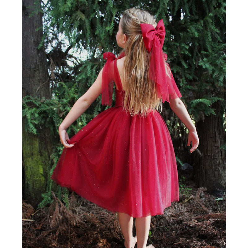 Rosie dress in Christmas crimson is worn by a young girl outside, along with matching girls red bow.