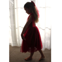 Rosie Christmas dress in wine crimson is worn by a young girl, showing the soft tulle wine skirt and matching wine bow hair clip.