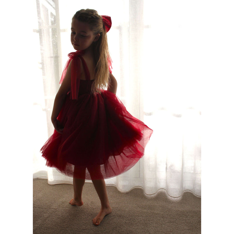 Young girl twirls wearing our Rosie crimson flower girl dress or Christmas dress. She also wears a matching girls large bow.