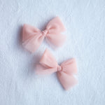 Small pigtail tulle bows in peachy blush.