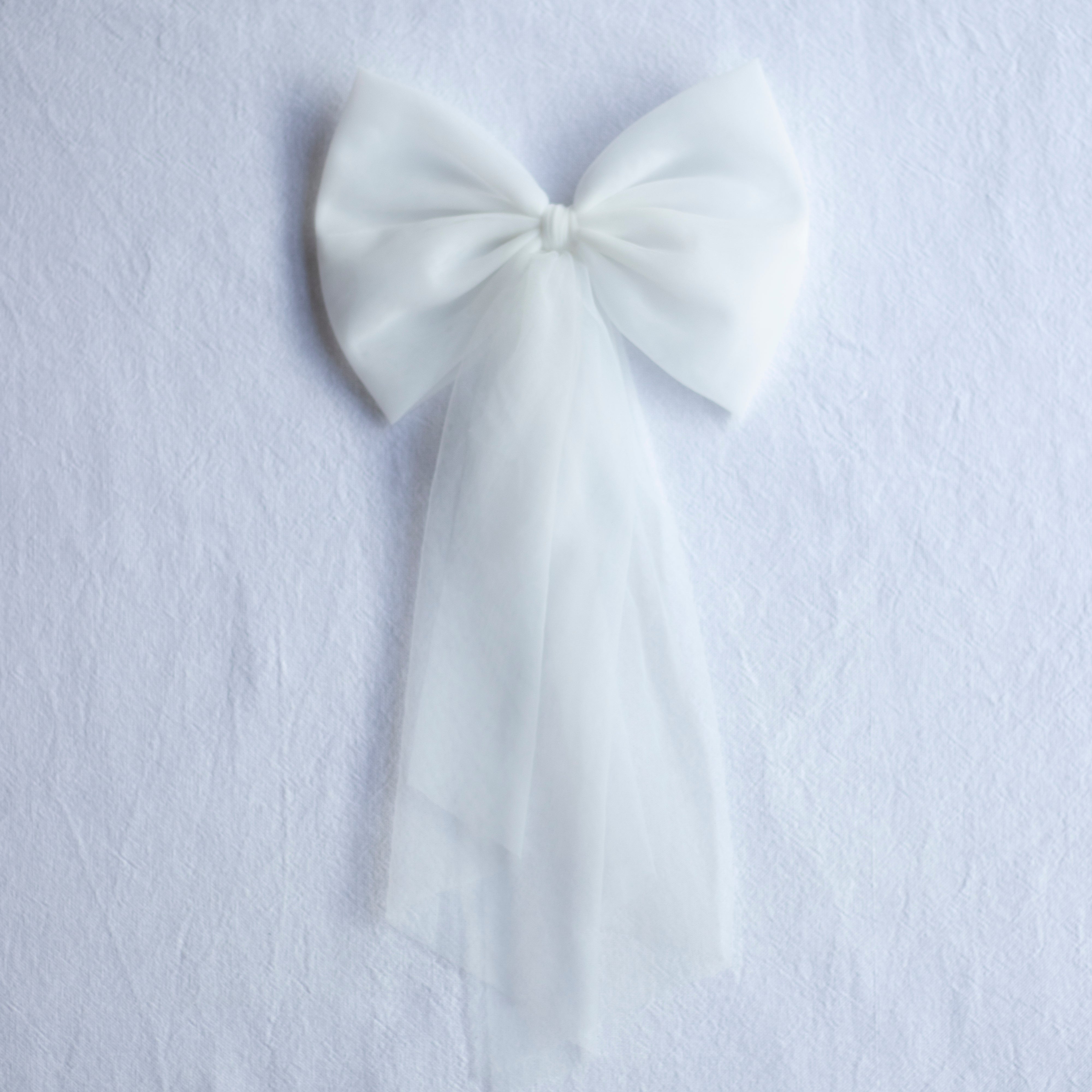 Large tulle bow clip in ivory with long tulle tails. Perfect to match a flower girl dress or girls party dress.