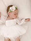 White baby flower girl dress, Wren dress, is worn by a toddler.